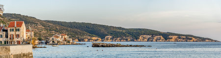 Panoramic view of Komiza coastline rock cliff on Vis Island in Croatia summer sunsetの写真素材