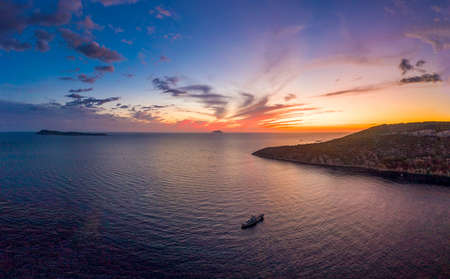 Aerial drone shot of boat drifting in Adriatic sea with sunset burning sky on Komiza over Vis Island in Croatia Summerの写真素材