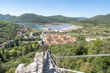 Narrow stone stair on Wall of Ston on hill with view of sault field in Croatia summerの写真素材