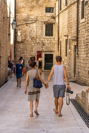 Dubrovnik, Croatia - Aug 20, 2020: Tourist couple with camera walk in old town street in summerのeditorial素材