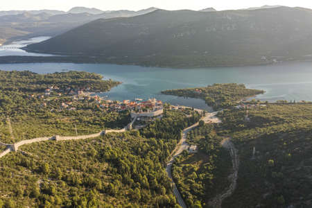 Aerial drone shot of City Wall of Ston over hill to Mali Ston in Croatia summer morning sunriseの写真素材