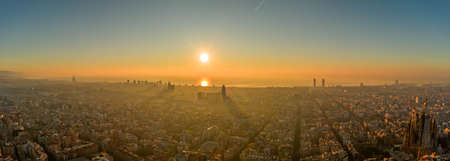 Panoramic aerial drone shot of Barcelona sea horizon in sunrise golden hour in foggy Spain winterの写真素材