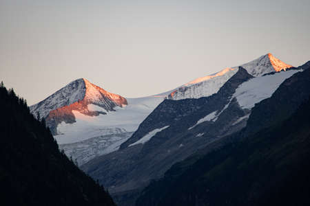 The last hours of sunshine of the day shine on the snow-covered top of the mountain "GroÃvenediger"の写真素材