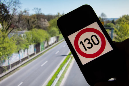 A speed limit symbol of 130 km per hour on a smartphone in front of a German autobahn