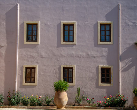 facade of an old house with windows, a pot of flowers on the wallの写真素材