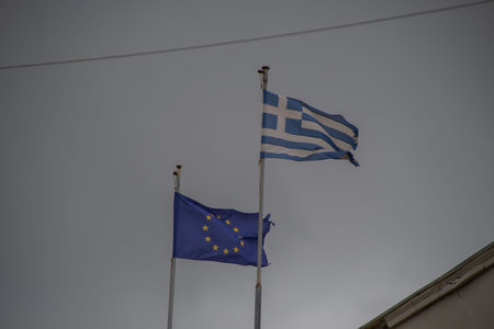 The Greek flag and the flag of the European Union are waving in the wind