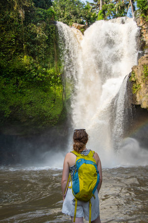 Woman looking at a waterfall in the jungle of Bali, Indonesiaの写真素材