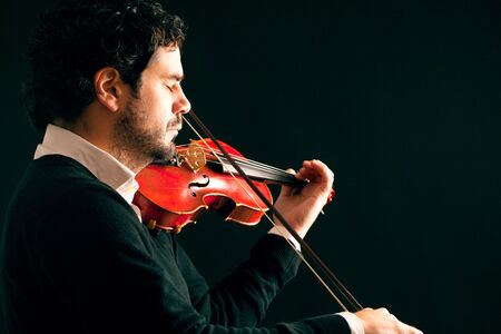 Musician playing violin in black background.の写真素材