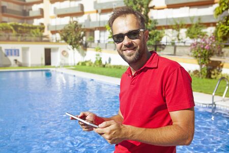 Man using a tablet at the poolside.の写真素材