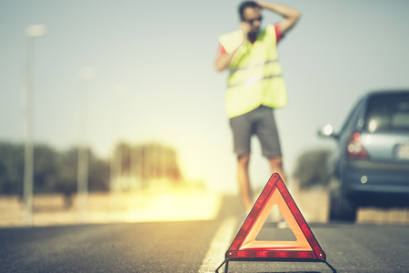 Emergency triangle with man and stopped car in the background. Vintage style.の写真素材