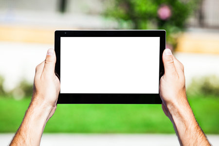 Hands holding a tablet. Copy space on the screen.