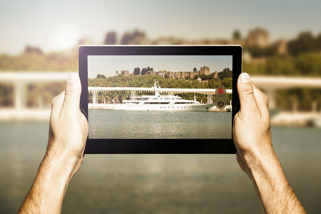 Taking photo with a tablet. Luxury yacht on the scene.の写真素材