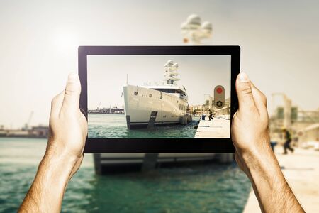 Taking photo with a tablet. Luxury yacht on the scene.の写真素材