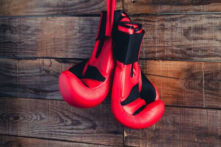 Two red boxing gloves in a wooden background wall.の写真素材