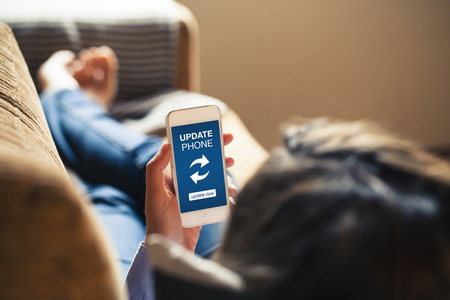 Woman holding a mobile phone while lying at home. Update phone notification in the screen.の写真素材