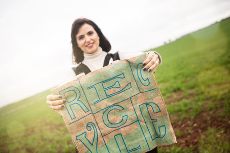 Brunette woman portrait, holding a recycling bag in the countryside.
