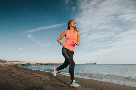 Running woman. Woman runner jogging during outdoor workout at the seashore.の写真素材
