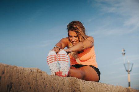Blonde woman stretching touching feet with hands.