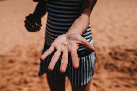 Woman holding a small shell in the hand at the coast line.の写真素材