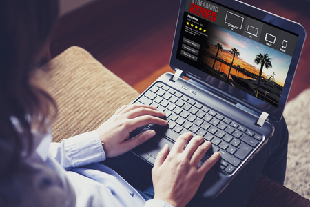 Woman watching TV series in a laptop computer through streaming website.の写真素材