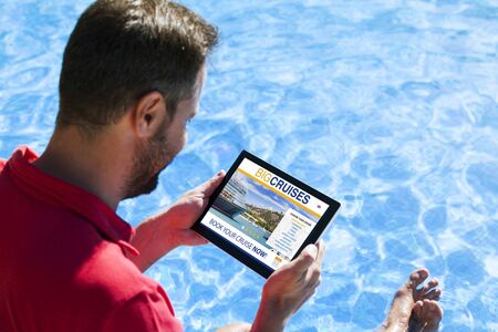 Man booking cruise travel by internet with a tablet at the swimming poolの写真素材