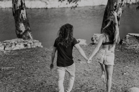 Couple in their backs walking happy towards a lake in natureの写真素材