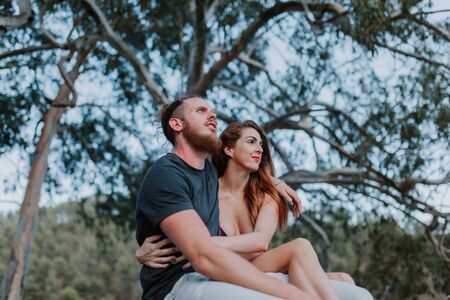 Young real couple sitting and embracing while looking at natureの写真素材