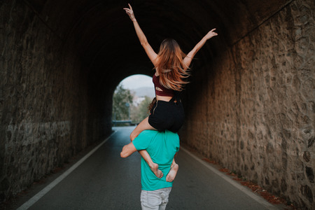 Young rad couple walking on their backs into a tunnel across the roadの写真素材