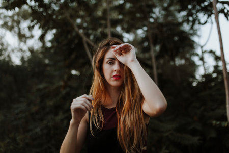 Woman posing in nature with a hand in the foreheadの写真素材