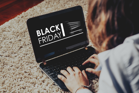 Black Friday special sales in a laptop screen. Woman shopping by internet with a computer.の写真素材