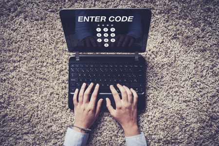 ENTER CODE in a laptop screen placed on a carpet. Hands typing in the keyboard.の写真素材
