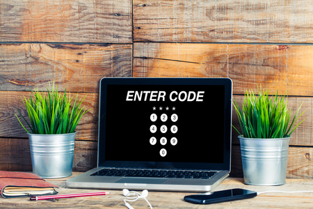 ENTER CODE in a laptop screen placed on a wooden deskの写真素材