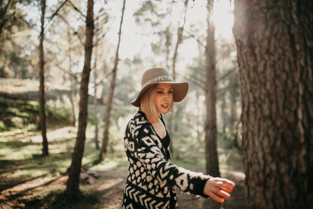 Woman taking a walk in the middle of a pine tree forest, and reaching to a pine tree trunkの写真素材