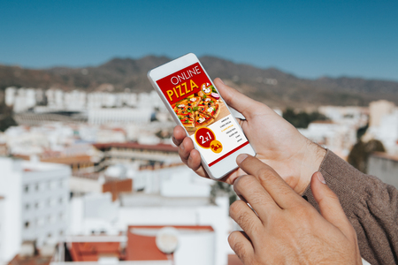 Man holding a mobile phone in the hand with Pizza shopping app in the screen.の写真素材