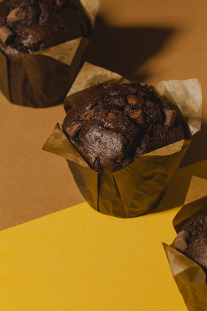 Bunch of chocolate muffins on yellow and brown background.の写真素材