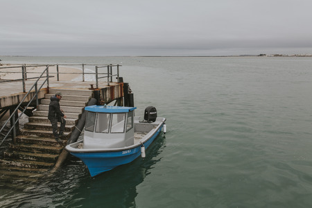 Armona Island, Portugal - March 23, 2018: Man boarding in a little blue boat at Armona Island pier in a cloudy day, in Olhao, Portugal.のeditorial素材