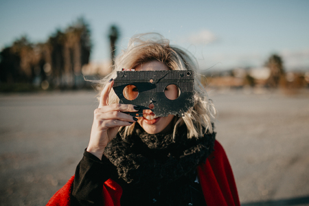 Blonde alternative woman playing with a VHS tape outdoors at sunset. Creative filmmaker concept.の写真素材