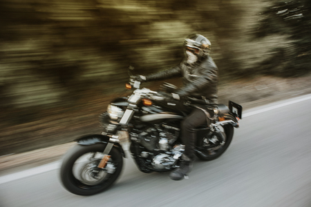 Blurry motion image of man riding a black American motorcycle on the road.の写真素材