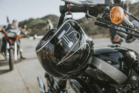 Close up of black helmet hanging from a classic black motorcycle handlebar.の素材 [FY310105414985]