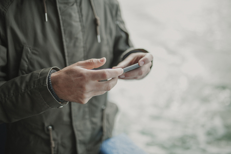 Close up of man hands holding a mobile phone while travel in a boat.の写真素材