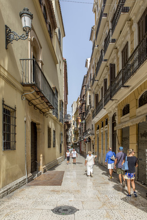 MALAGA, SPAIN - September 2nd, 2018: Tourists walking across a narrow lane during a journey in the city center of Malaga, Spain.のeditorial素材