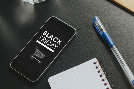 Black Friday marketing design in a mobile phone screen over a black business table.の写真素材