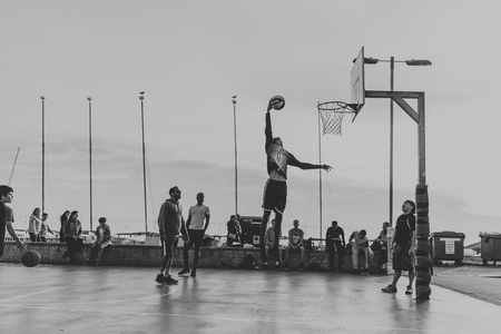 BRIGHTON, ENGLAND - October 24th, 2018: Young people playing basketball at the courts placed on the Brighton beach promenade, at sunset.のeditorial素材