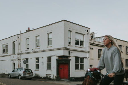 BRIGHTON, ENGLAND - October 24th, 2018: City view of common street corner while girl cross the scene by bicycle.のeditorial素材