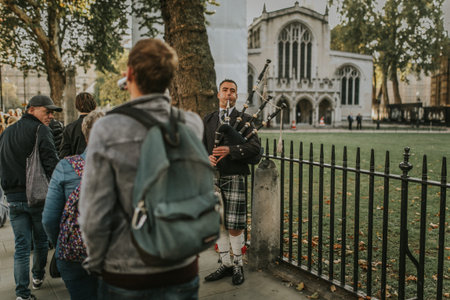 LONDON, ENGLAND - October 25th, 2018: Bagpiper playing pipe at Westminster Abbey entrance, while...