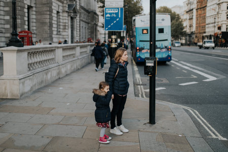LONDON, ENGLAND - 25th October, 2018: Mom holding her daughter hand and waiting on de sidewalk before crossing the street in London, England.のeditorial素材