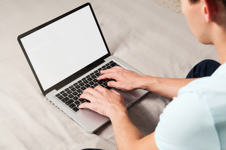 Man using a laptop sitting at home with white blank screen.の写真素材