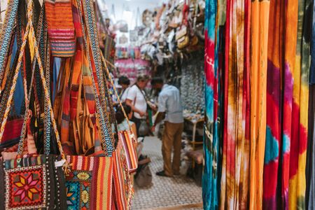 Rissani, Morocco - September 18th, 2019: Textile shop and man and woman talking about clothes prices in Rissani bazaar market, in Morocco.のeditorial素材