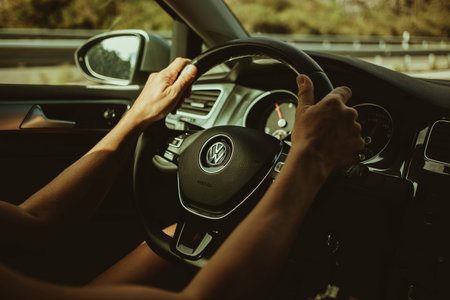 Oviedo, Spain - August 25th, 2020: Woman hands driving a Volkswagen Golf 7, holding the steering...