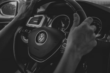 Oviedo, Spain - August 25th, 2020: Woman hands driving a Volkswagen Golf 7, holding the steering...